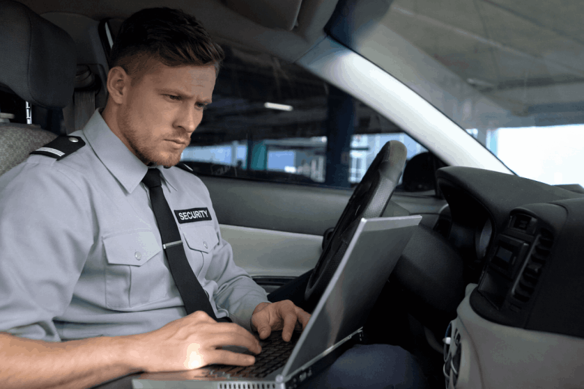 Security guard conducting mobile patrol duties in Toronto while completing a digital report inside a patrol vehicle